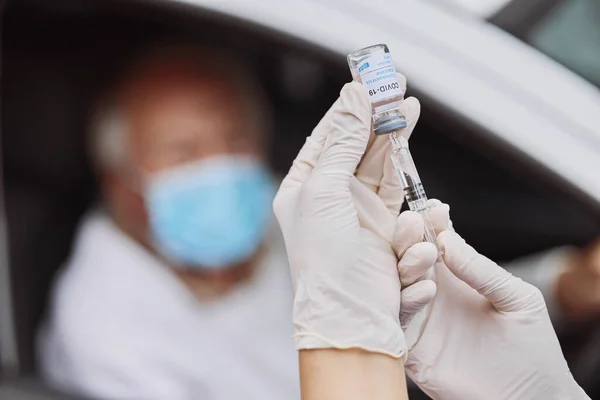 Lekarstwo na śmiertelną chorobę. Strzał nierozpoznawalnego pracownika służby zdrowia pobierającego płyn z fiolki strzykawką w miejscu przejazdu przez miejsce szczepienia. — Zdjęcie stockowe