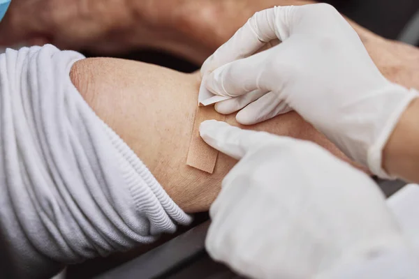 Está oficialmente vacinado. Tiro de um profissional de saúde irreconhecível que aplica um penso rápido a um braço de doentes num local de vacinação. — Fotografia de Stock