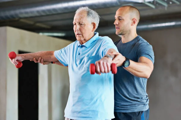 Es wird einfacher. Aufnahme eines Physiotherapeuten, der einem älteren Mann mit Gewichten hilft. — Stockfoto