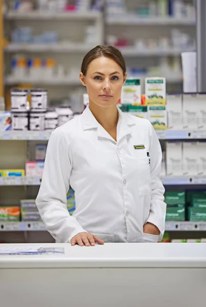 El tratamiento comienza con su farmacéutico local. Retrato de un joven farmacéutico atractivo de pie en el mostrador de prescripción. — Foto de Stock