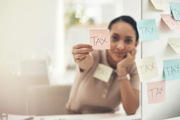 Esteja ciente de diferentes prazos de depósito. Tiro de uma jovem empresária segurando uma nota com "imposto" escrito em um escritório. — Fotografia de Stock