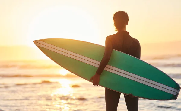 Ideje meglovagolni egy újabb hullámot. Visszapillantó kép egy nőről, aki szörfdeszkát cipel a parton.. — Stock Fotó