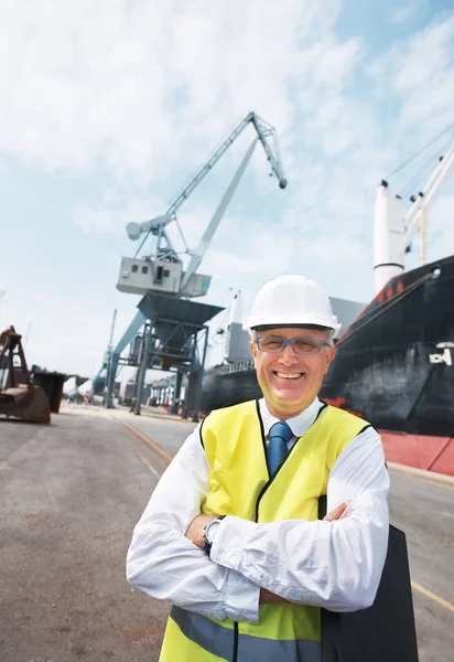 Mi trabajo me trae una alegría tremenda. Retrato de un trabajador portuario parado en el puerto en medio de la actividad de la industria naviera. — Foto de Stock