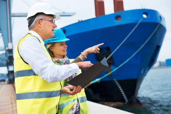 Mirando hacia fuera para la nave derecha. Dos trabajadores portuarios confiriendo entre sí mientras inspeccionan el puerto. — Foto de Stock