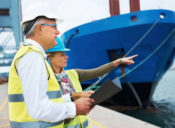 Caza de barcos. Dos trabajadores portuarios confiriendo entre sí mientras inspeccionan el puerto. — Foto de Stock