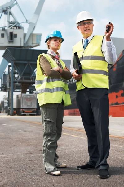 La comunicación efectiva entre compañeros de trabajo es vital. Dos ingenieros discuten la planificación en un sitio mientras están en el astillero. — Foto de Stock