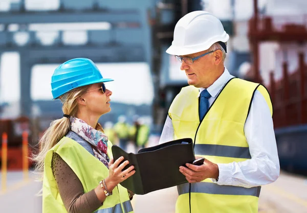 Samenwerken creëert succes. Twee collega 's die in een haven staan en werk bespreken... — Stockfoto