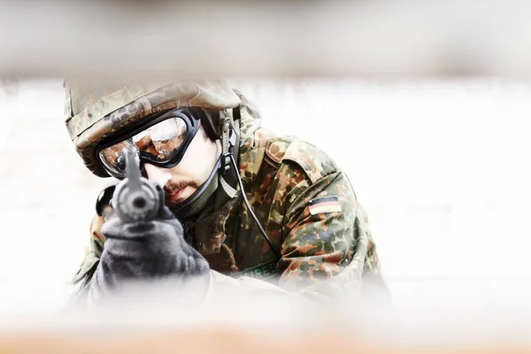 Unter Verschluss halten. Nahaufnahme eines Soldaten, der seine Waffe durch einen Schlitz im Vordergrund in die Kamera richtet. — Stockfoto