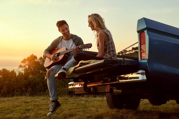 완전 한 조화를 이루는 사랑 과 여가. 여자 친구를 위해 기타를 치고 있는 젊은 남자 가 도로 여행중에 찍은 사진. — 스톡 사진