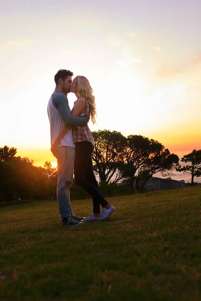 A captar o clima ao pôr-do-sol. Tiro de um jovem casal afetuoso compartilhando um beijo ao pôr do sol. — Fotografia de Stock