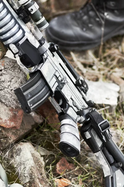 Braccia a riposo. Primo piano di una pistola automatica appoggiata a terra contro una roccia. — Foto Stock