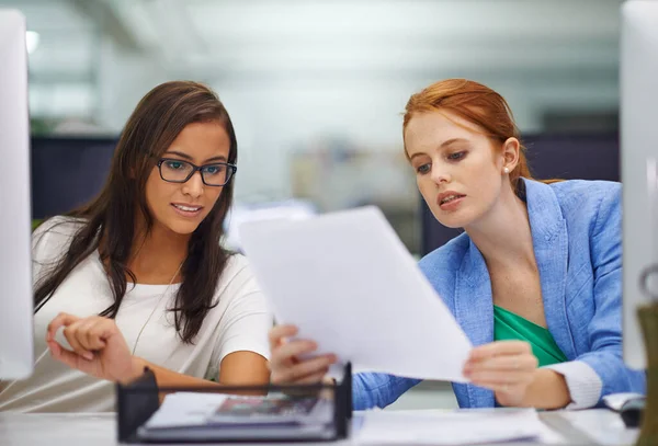 En caso de duda, pida consejo. Fotografía de dos atractivas hembras mirando algunos documentos de trabajo. — Foto de Stock