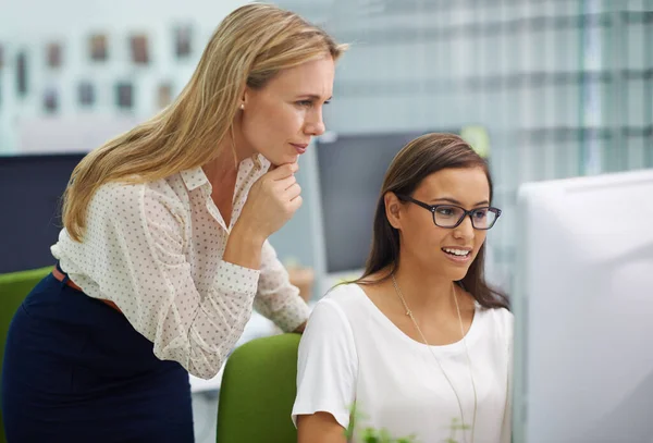 There are no stupid questions. Shot of two attractive female colleagues in a quandary over some work on a computer in an office setting. — Stock Photo, Image