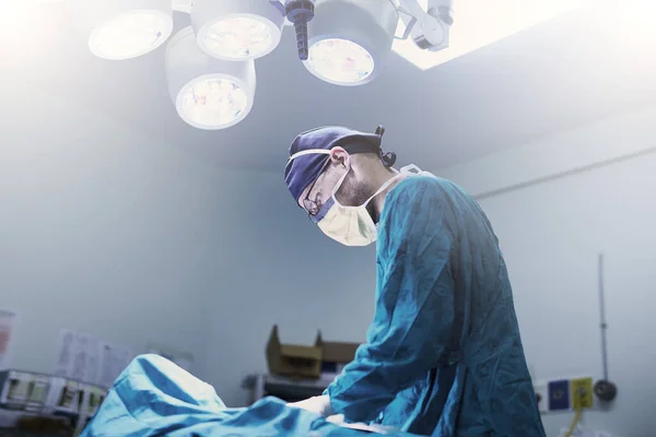 Faz isso com cuidado. Tiro de um jovem cirurgião focado a fazer uma cirurgia num paciente numa sala de operações. — Fotografia de Stock