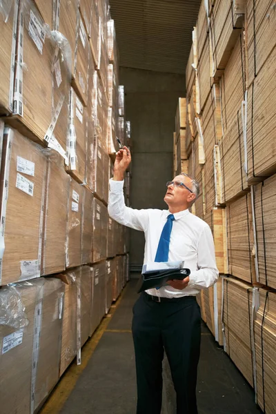 De klus klaren is essentieel. Een manager in een gangpad in een magazijn die de kartonnen containers onderzoekt. — Stockfoto
