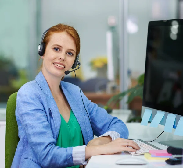 Listo cuando lo estés. Foto de una atractiva mujer pelirroja mujer de negocios con auriculares en una oficina. — Foto de Stock