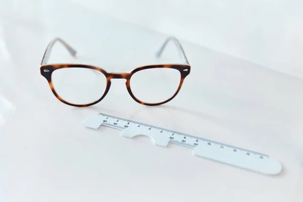 La clarté vient par paires. Prise de vue d'une paire de lunettes et d'une règle pd dans un bureau d'optométristes. — Photo