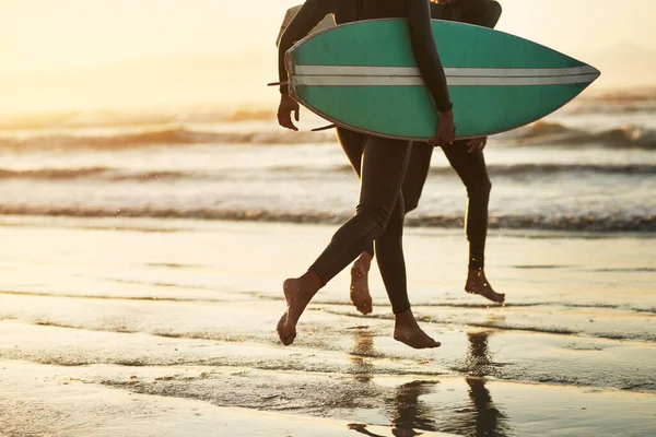 Бегут в дикий океан. Снимок неузнаваемой молодой пары, которая занимается серфингом на пляже. — стоковое фото