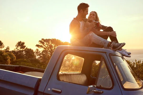 Romance no topo da colina ao pôr-do-sol. Tiro de um jovem casal afetuoso em uma viagem de carro. — Fotografia de Stock