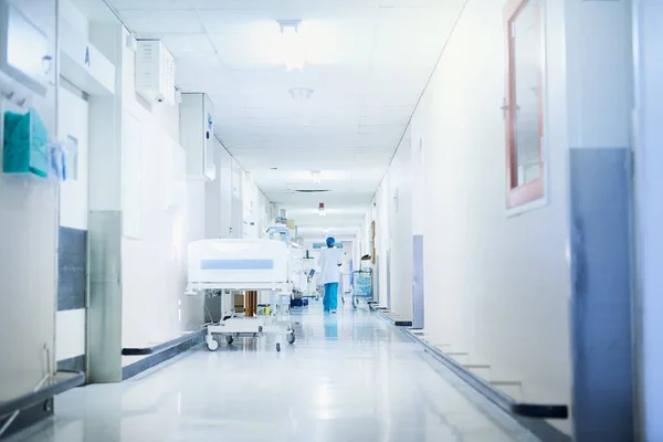Por aqui, para o bem-estar. Imagem retrospetiva de um cirurgião a caminhar por um corredor do hospital. — Fotografia de Stock