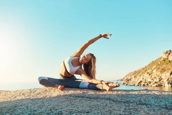Le yoga te changera. Prise de vue d'une jeune femme sportive pratiquant le yoga sur la plage. — Photo