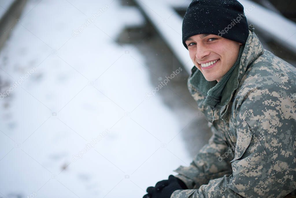 Its cold but I stay committed. Shot of a young soldier sitting outside on a snowy day.