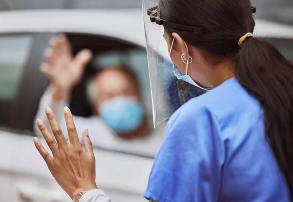 A bientôt. Prise de vue d'un travailleur de la santé méconnaissable agitant un patient lors d'un trajet à travers le site de vaccination. — Photo