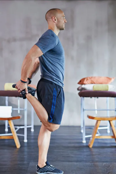 Limpiando. Una foto recortada de un entrenador guapo estirándose antes de una sesión de entrenamiento. —  Fotos de Stock