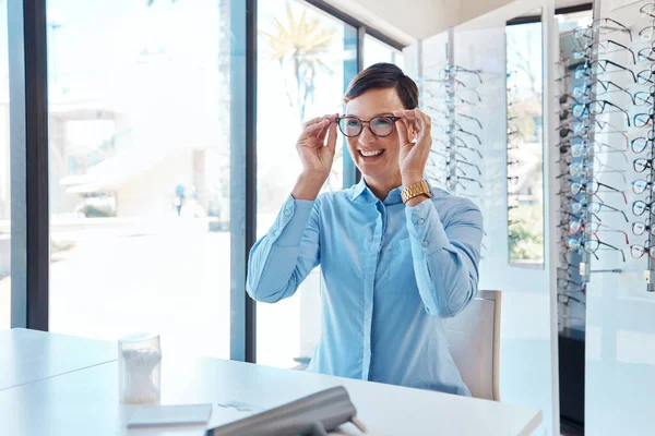 Estes óculos são espectaculares. Tiro de uma jovem mulher comprando um novo par de óculos em uma loja de optometrista. — Fotografia de Stock