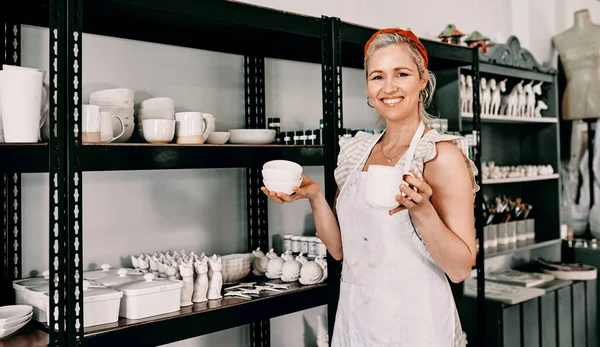 ¿Cuál te gusta? Retrato recortado de una atractiva mujer madura de pie y organizando su cerámica en un estante en su taller. — Foto de Stock