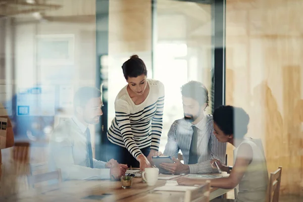 Framgång börjar här på kontoret. Genom glasbilden av en grupp kollegor som arbetar tillsammans på ett kontor. — Stockfoto