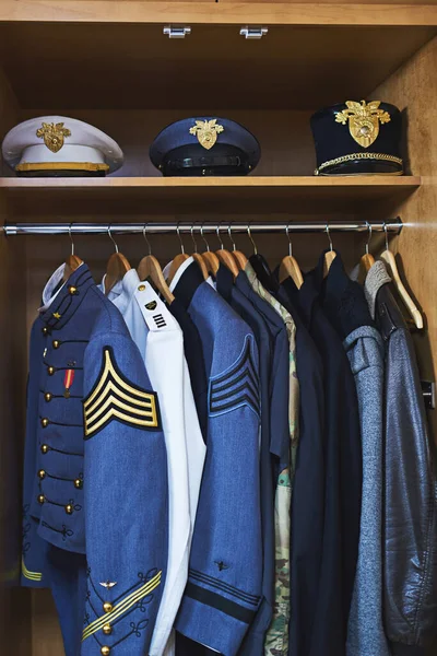 Ropa hecha para combate. Disparo de varias chaquetas militares y sombreros colgando en un armario. — Foto de Stock