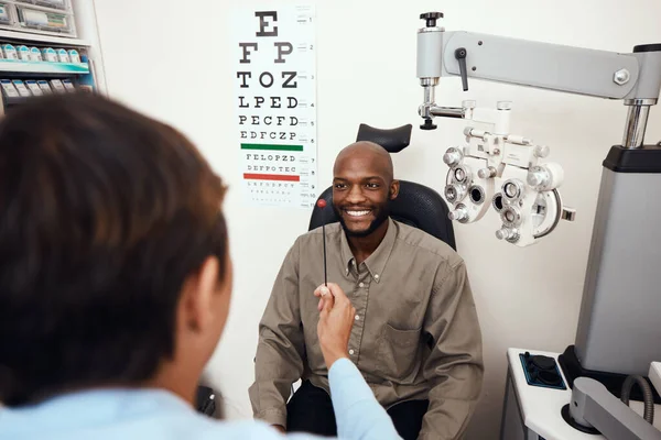 Een stap verwijderd van beter zicht. Schot van een jonge man met een oogtest uitgevoerd door een optometrist. — Stockfoto