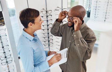 They fit perfectly. Shot of a an optometrist helping a young man choose a new pair of glasses. clipart