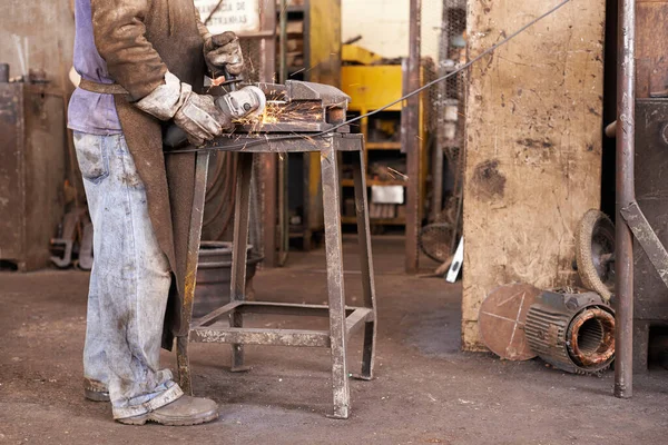 Там, де промисловість відповідає творчим... Чоловік шліфує шматок металу в майстерні . — стокове фото
