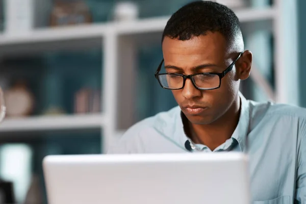 Empresários são muitas vezes homens muito ocupados. Tiro de um belo jovem empresário trabalhando em seu laptop durante um turno da noite no trabalho. — Fotografia de Stock