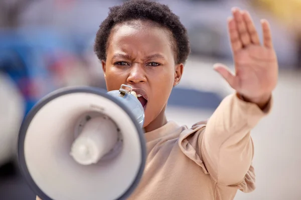 Kämpa för det du tror på. Skjuten av en ung kvinna med handen upp talar genom en megafon på en protest. — Stockfoto
