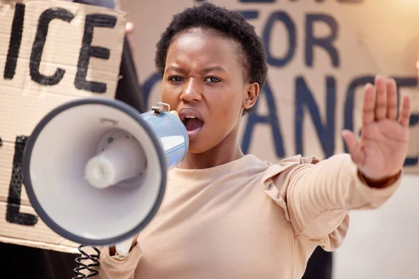 La fuerza es lo que necesitamos. Un disparo de una joven con la mano levantada hablando a través de un megáfono en una protesta. — Foto de Stock