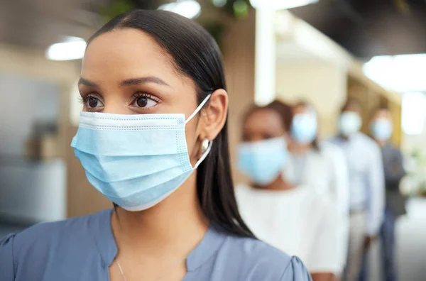 Fai pratica con cautela. Colpo ritagliato di una giovane donna d'affari attraente che indossa una maschera mentre in piedi alla testa di una coda nel suo ufficio. — Foto Stock