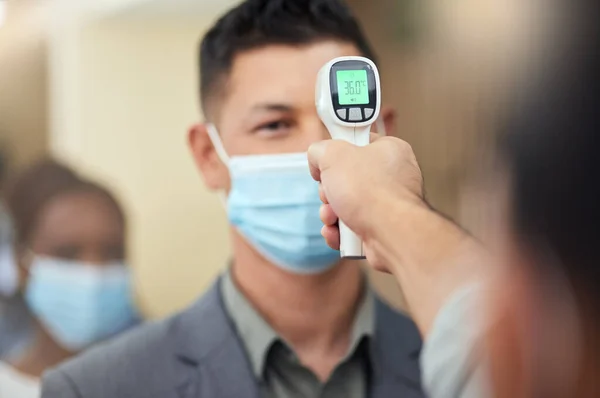 Its the new normal. Cropped shot of a handsome mature businessman wearing a mask and having his temperature taken while standing at the head of a queue in his office. — Stock Photo, Image