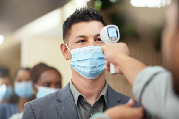 Going through covid screening. Cropped shot of a handsome mature businessman wearing a mask and having his temperature taken while standing at the head of a queue in his office. — Stock Photo, Image