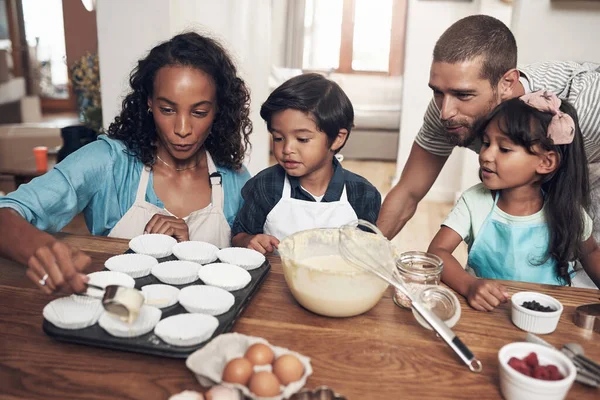 Ga naar huis en hou van je familie. Shot van een jong paar bakken thuis met hun twee kinderen. — Stockfoto