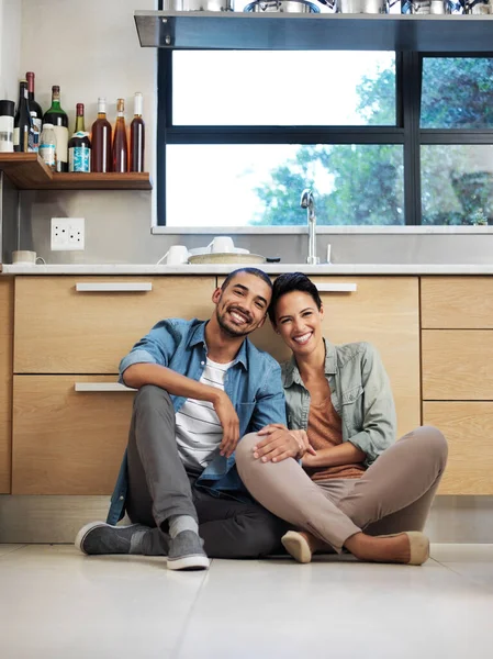 Щасливі вдома разом. Портрет усміхненої молодої пари, що сидить разом на підлозі кухні . — стокове фото