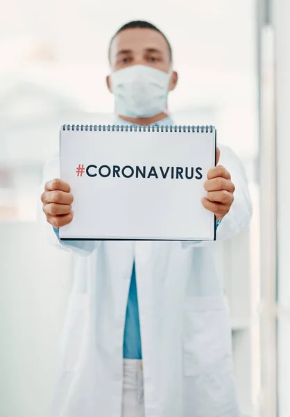 Reden wir über das Coronavirus. Porträt eines jungen Wissenschaftlers mit einem Schild mit CORONAVIRUS darauf in einem modernen Labor. — Stockfoto
