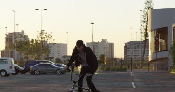 Das ist nichts, was man lieber tun sollte. 4k-Video eines jungen BMX-Bikers beim Tricksen auf seinem Fahrrad auf einem städtischen Parkplatz. — Stockvideo