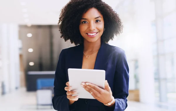 Updating my work schedule. Cropped portrait of an attractive young businesswoman standing alone and using a tablet while in the office during the day. — Stock Photo, Image