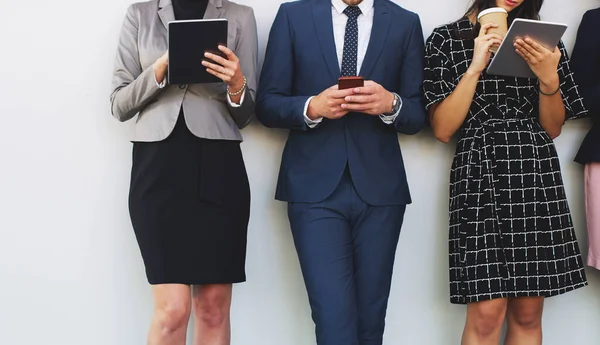 La tecnología ahora nos pertenece. Recorte de tres empresarios irreconocibles que utilizan la tecnología mientras están de pie en la oficina durante el día. — Foto de Stock