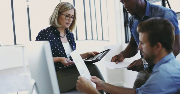 Lasst uns schnell lesen.... Schnappschuss von drei jungen Designern, die gemeinsam in ihrem Büro ein paar Papierkram erledigen. — Stockfoto