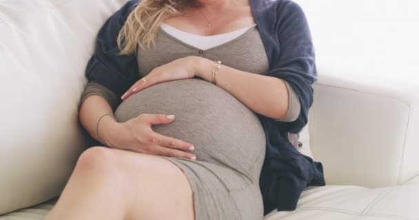 Tohle je moje první. 4K záběry ženy tření její těhotné břicho, zatímco relaxaci na pohovce doma. — Stock video