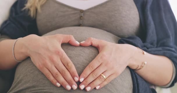 Эта шишка приносит много радости. 4k видео беременной женщины, формирующей форму сердца на животе. — стоковое видео